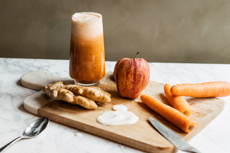 Carrot, ginger, Apple Super Skin Boost Smoothie in a glass with straw