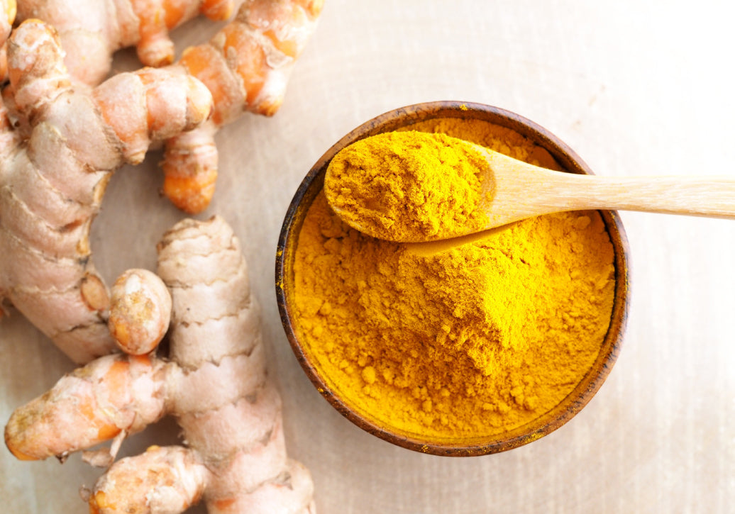 turmeric root next to a bowl with ground turmeric