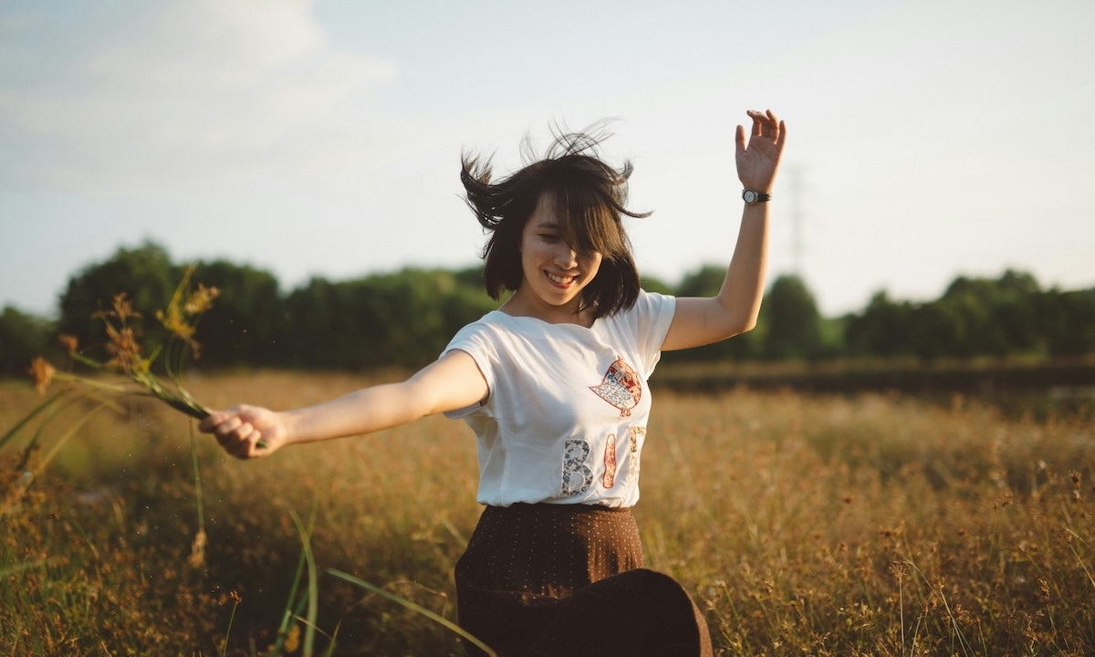 young woman dancing joyfully in a spring field